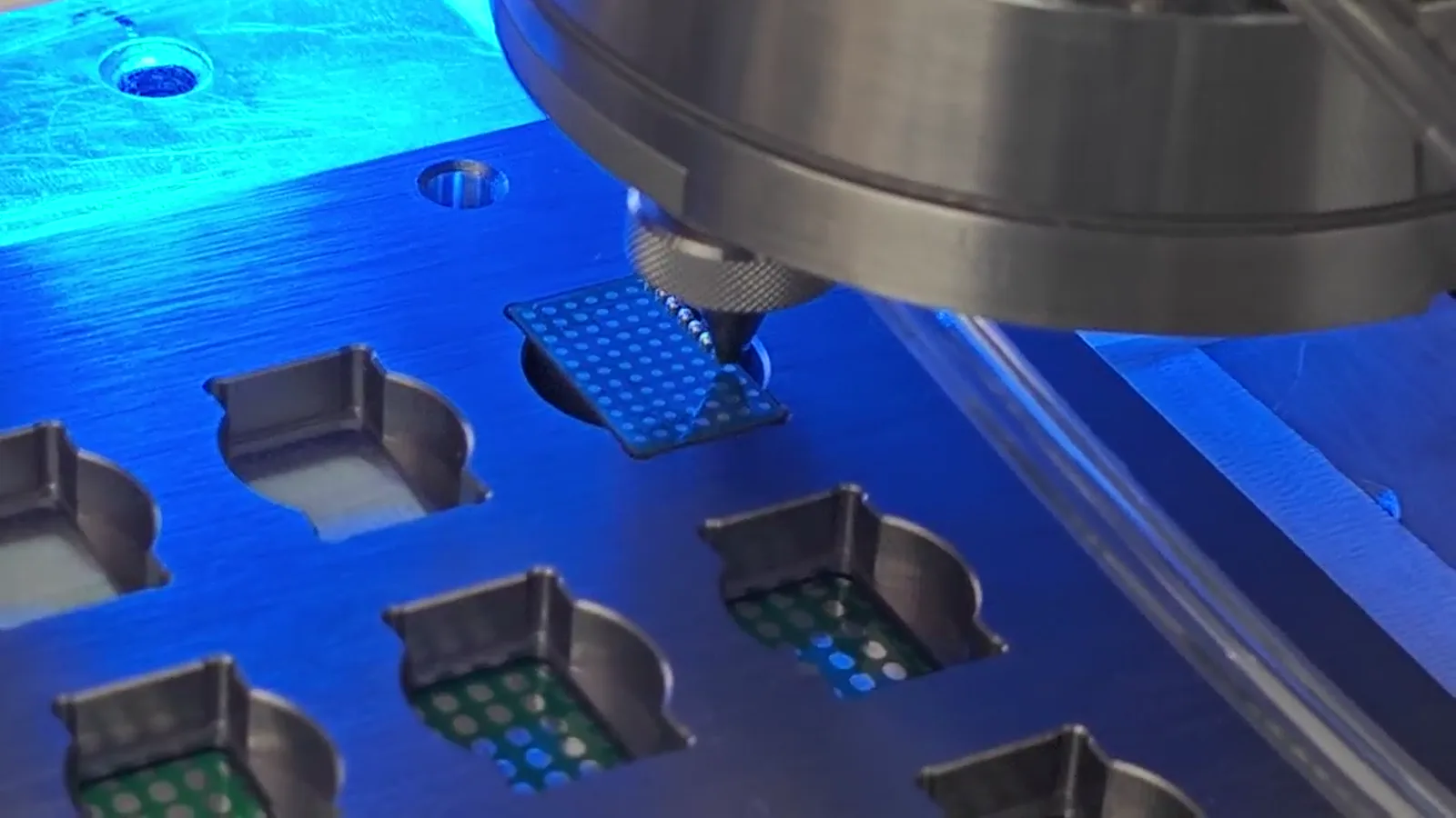 Jetting head processing a component in a blue fixture from supplied process video